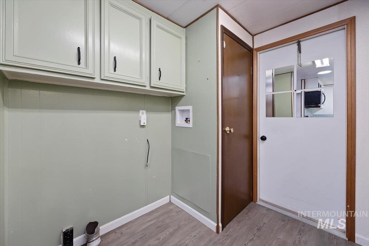 Laundry room with light wood-style floors, hookup for a washing machine, and cabinet space
