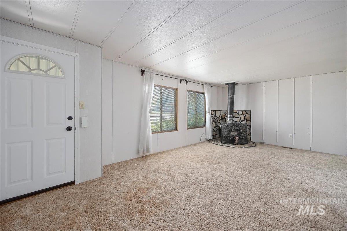 Entryway with a wood stove, carpet, and a decorative wall