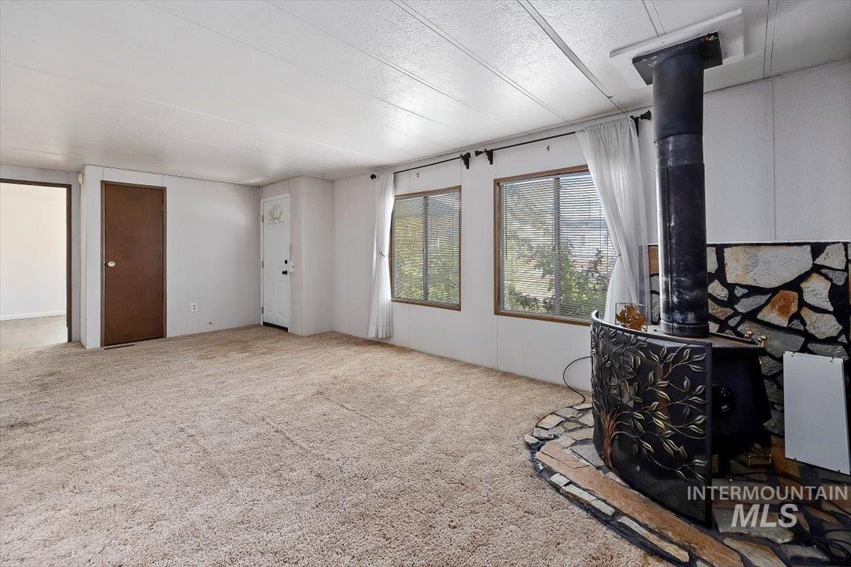 Carpeted living area with a wood stove and a textured ceiling