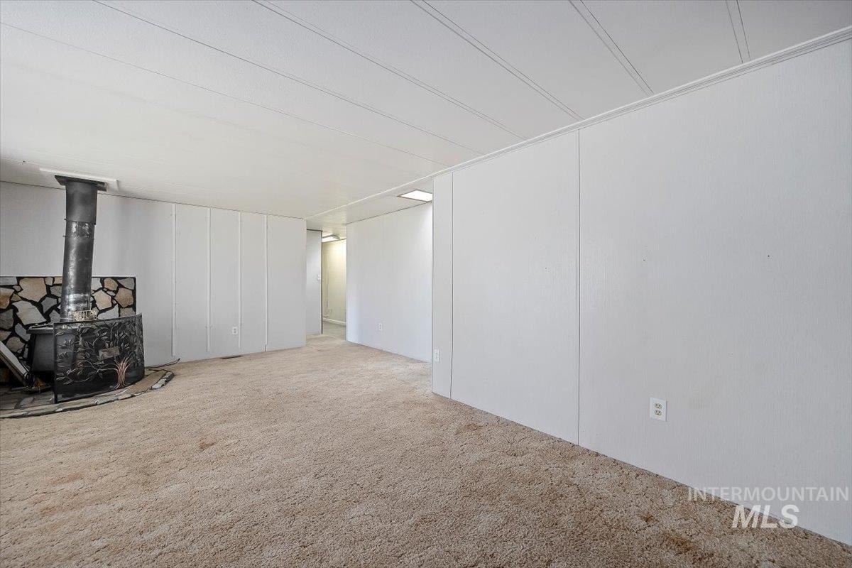 Unfurnished living room with a wood stove and carpet floors