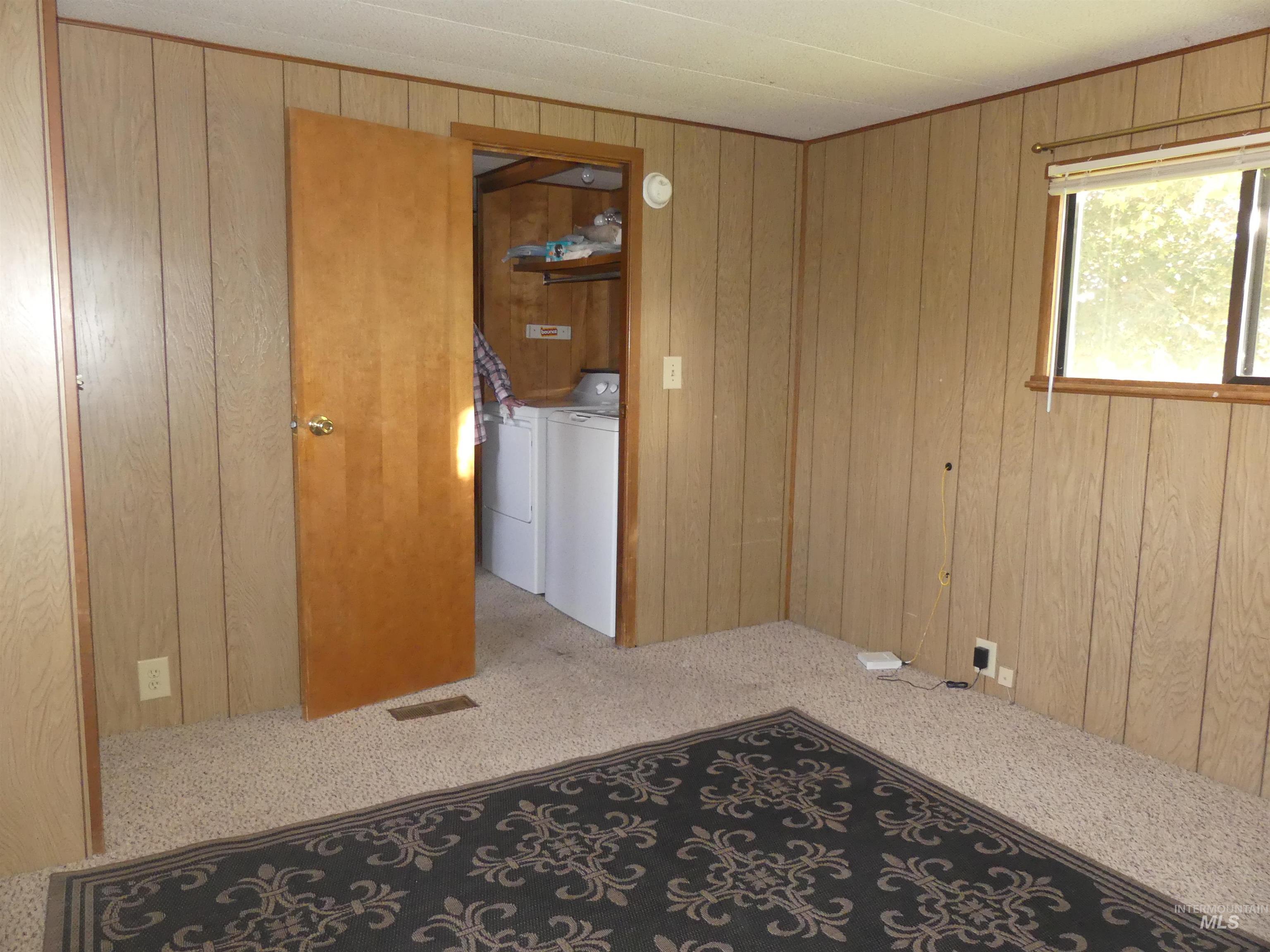 Carpeted empty room featuring wood walls and washer and dryer