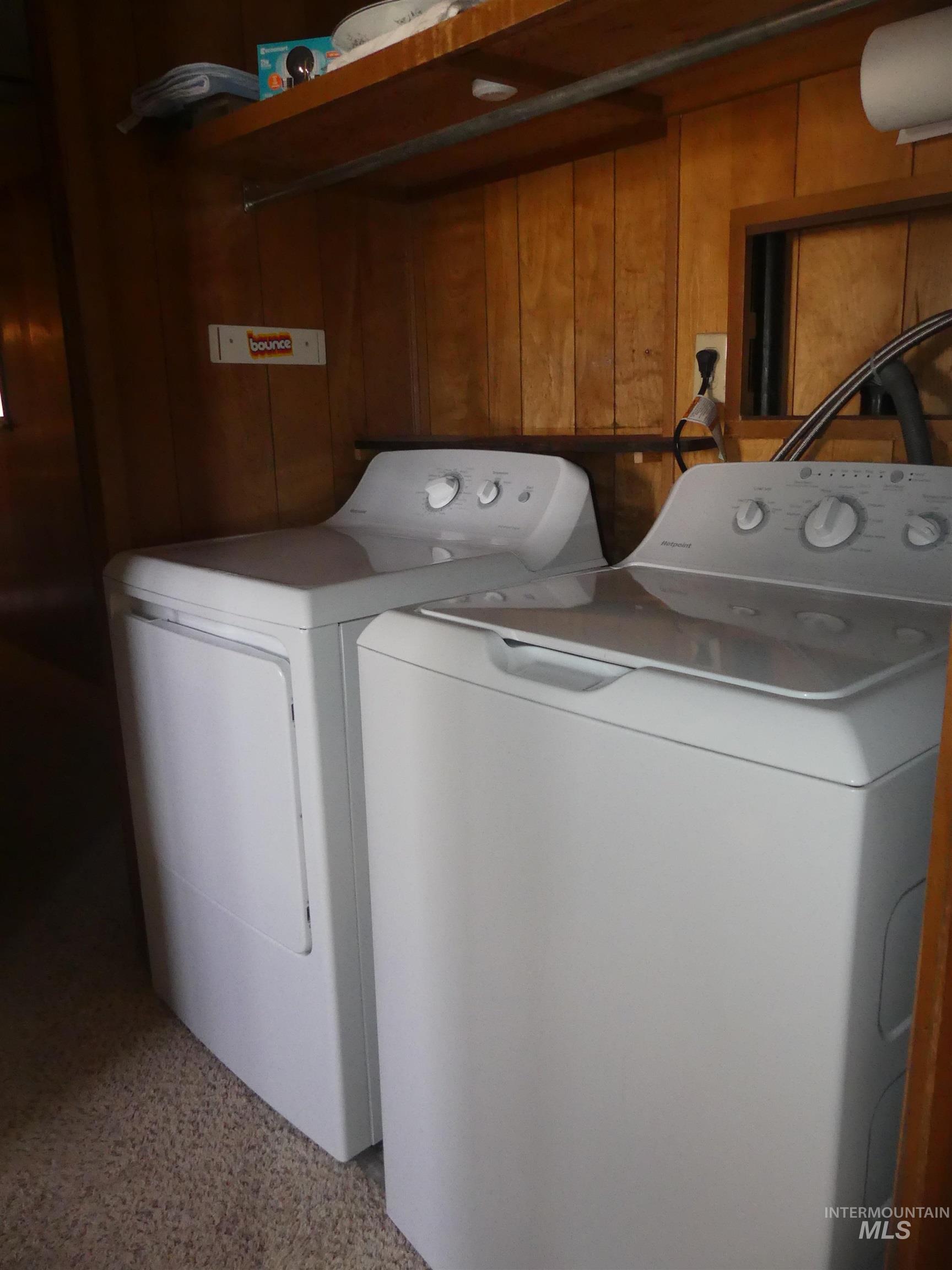 Laundry area with washing machine and clothes dryer and dark aggregate flooring