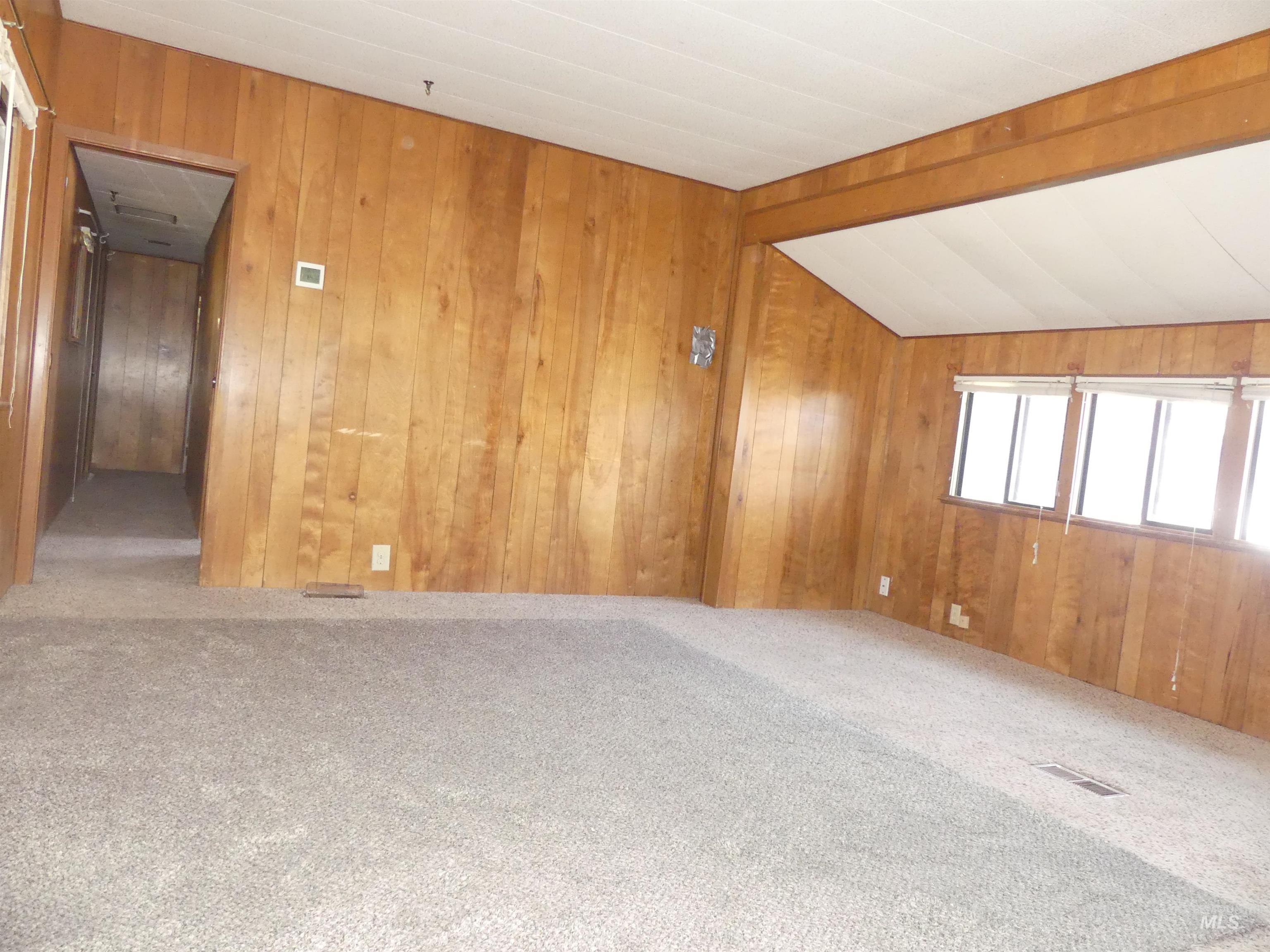 Carpeted spare room with wooden walls