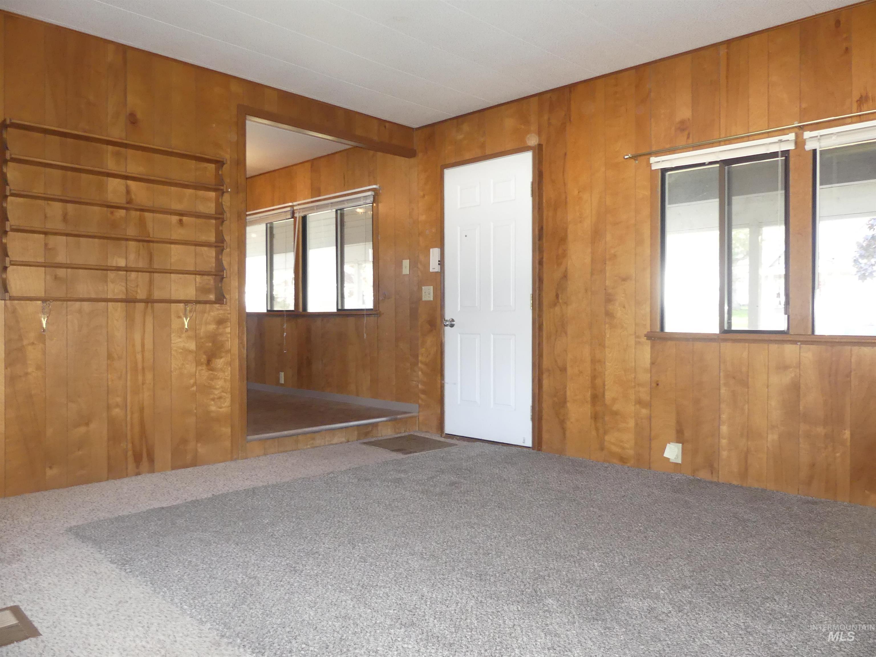 Carpeted spare room featuring wood walls