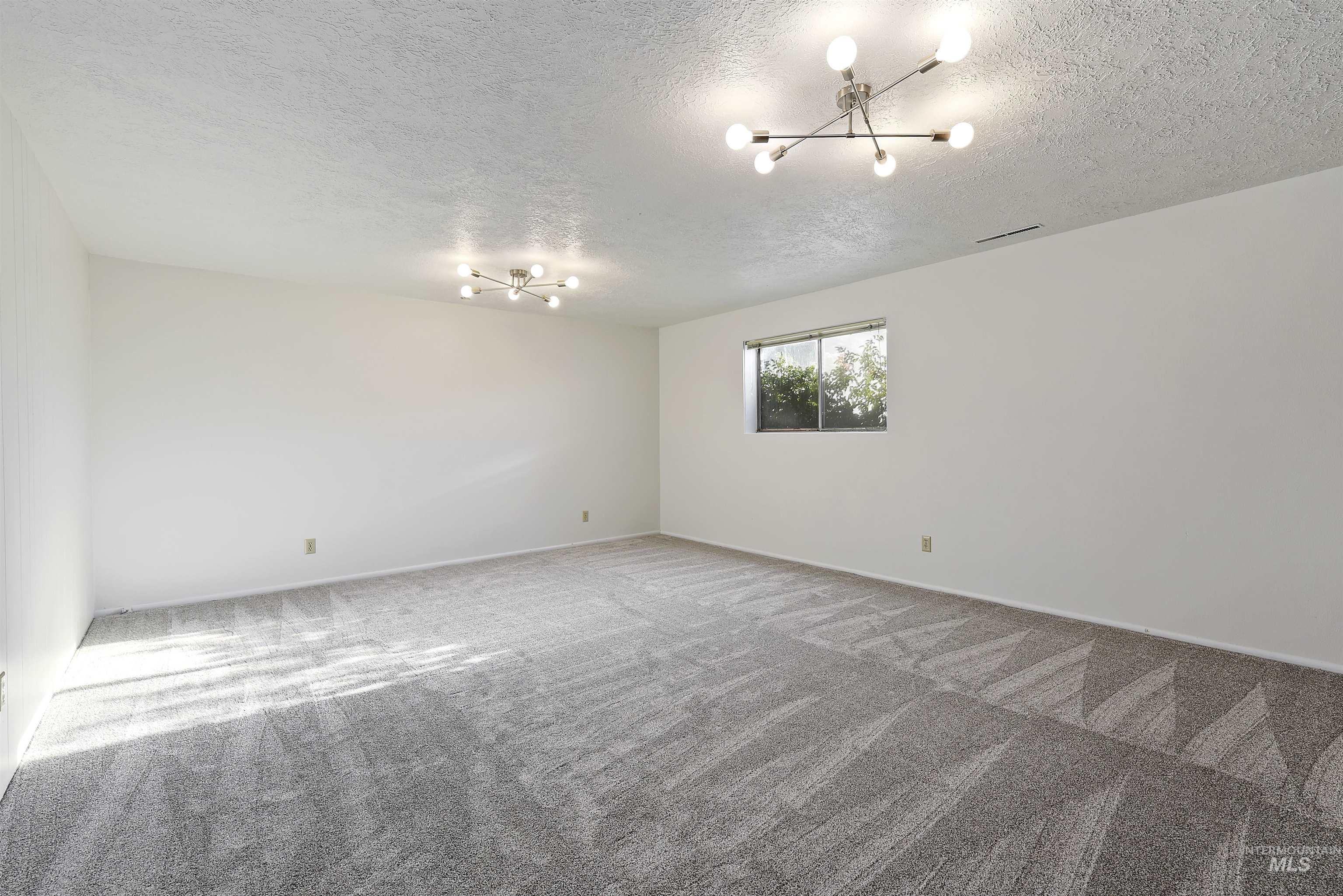 Spare room with carpet, a chandelier, and a textured ceiling