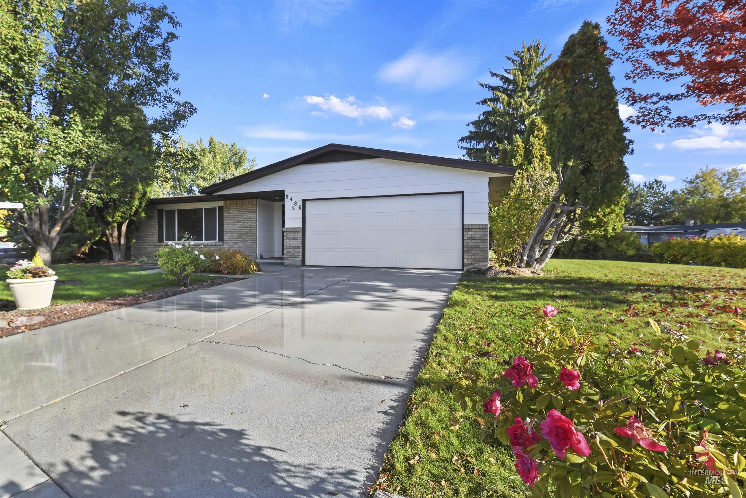 Ranch-style house with concrete driveway, brick siding, a garage, and a front lawn