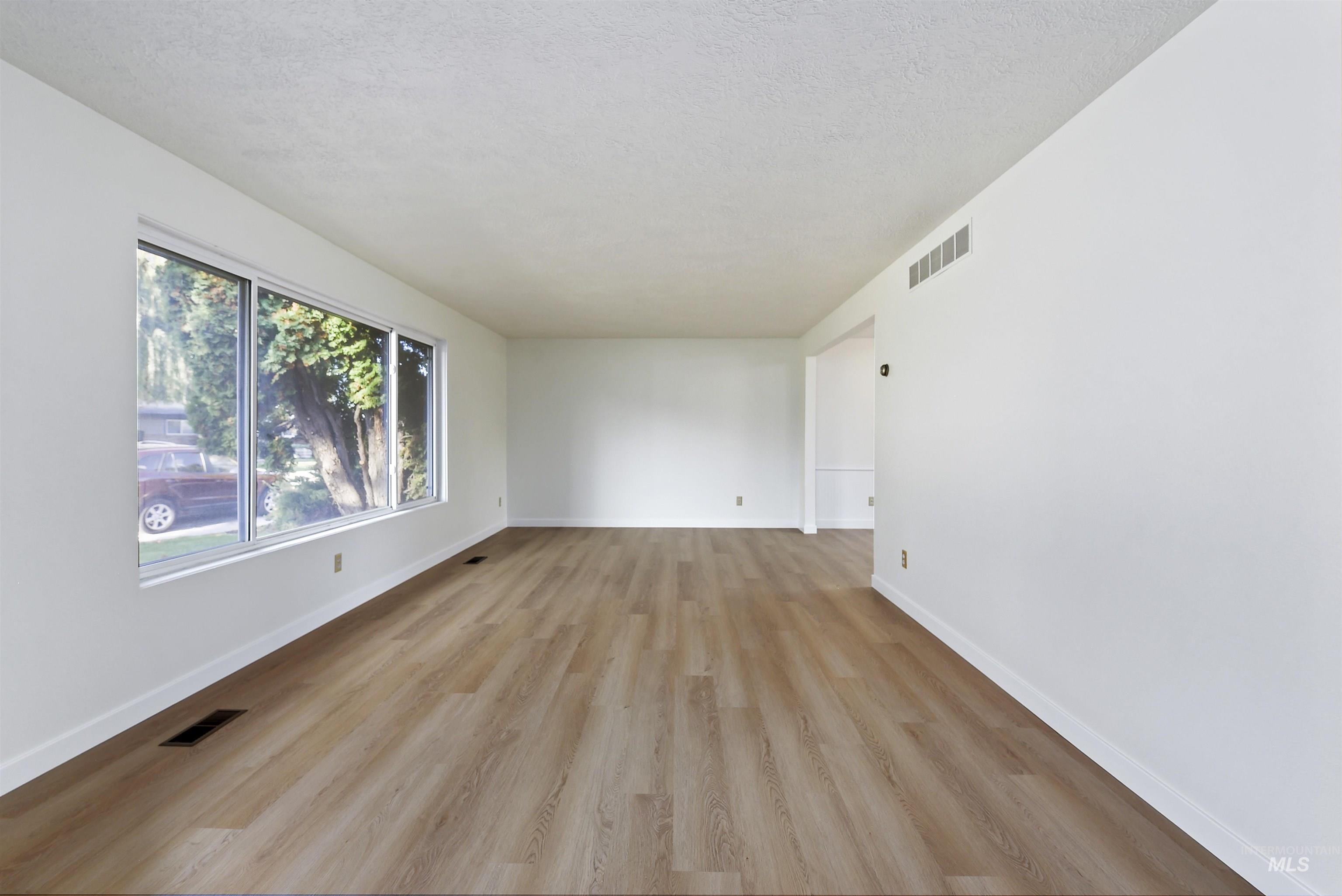 Empty room featuring light wood-style flooring and a textured ceiling