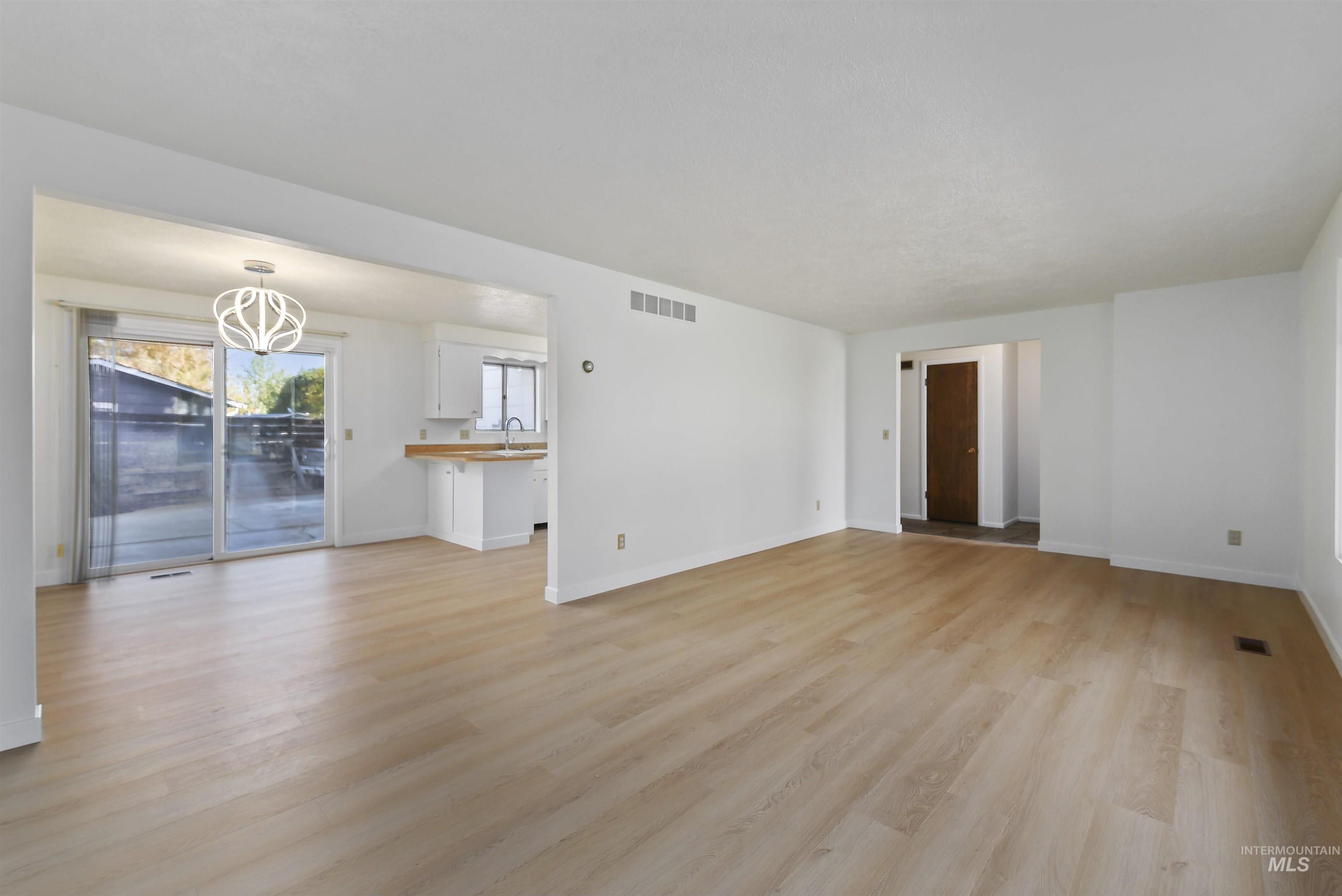 Unfurnished living room featuring light wood-type flooring and baseboards