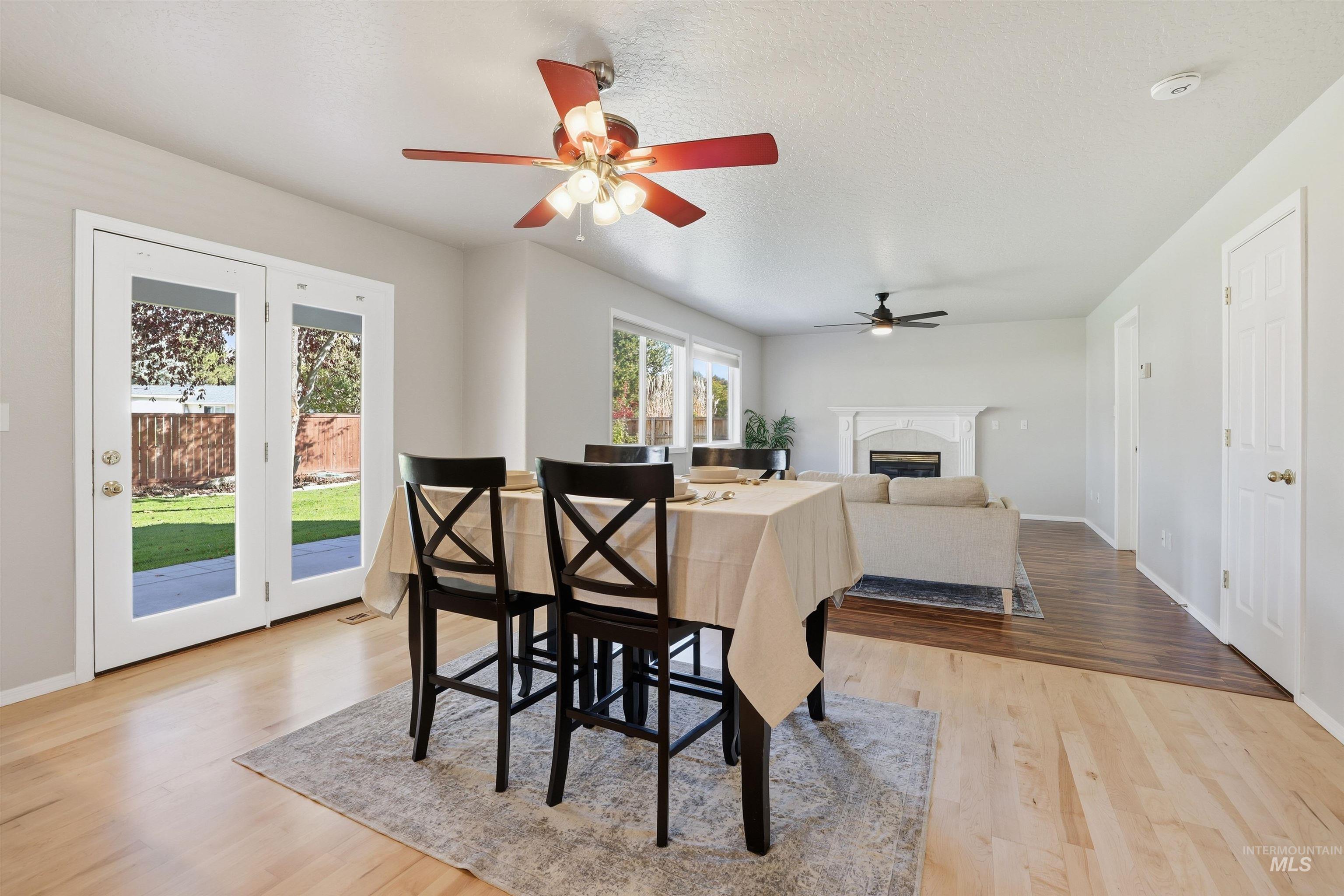 Dining space featuring a premium fireplace, light wood finished floors, a textured ceiling, and ceiling fan