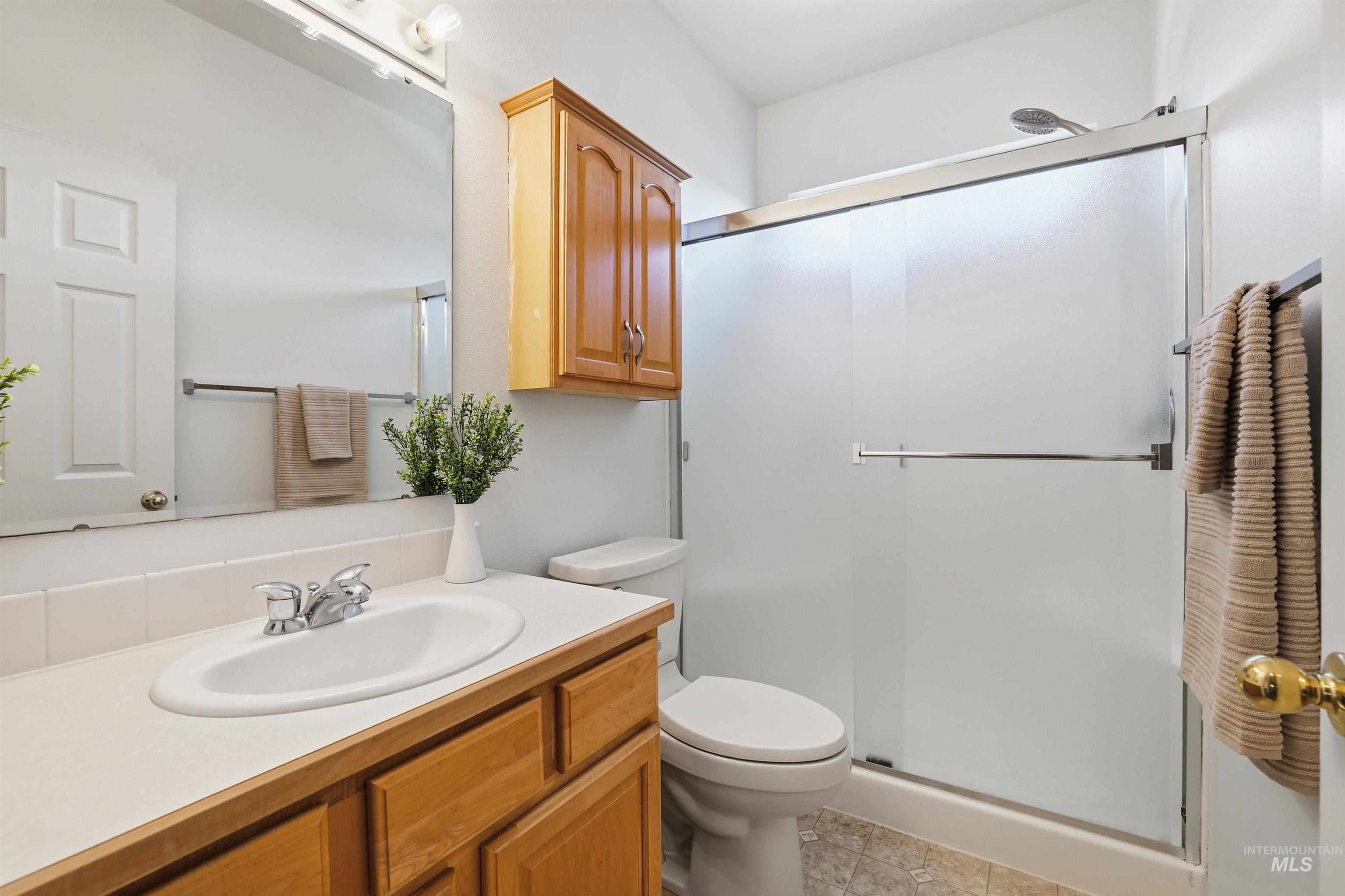 Bathroom with vanity, a shower stall, and light tile patterned flooring