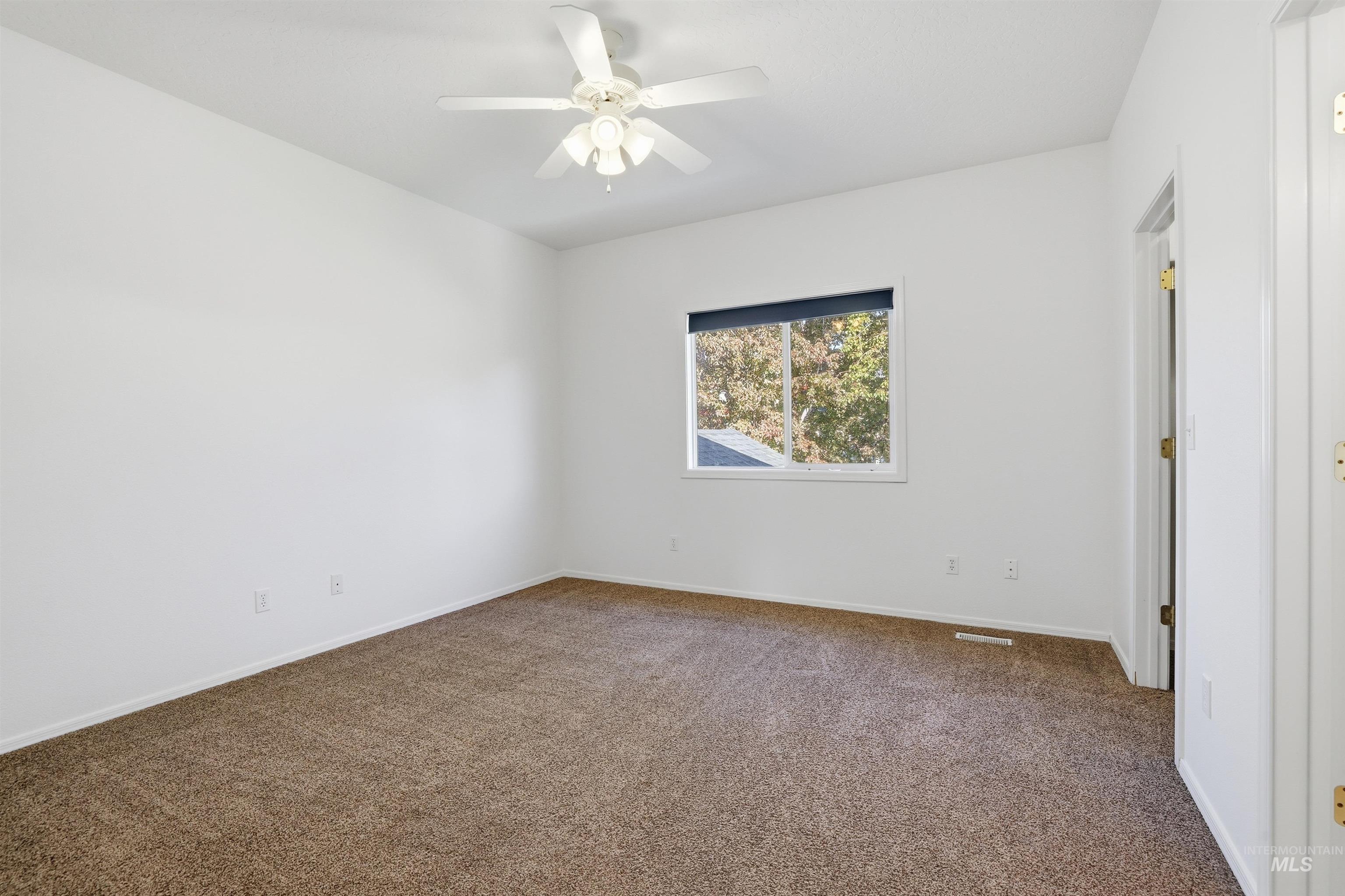 Unfurnished bedroom with dark colored carpet and a ceiling fan