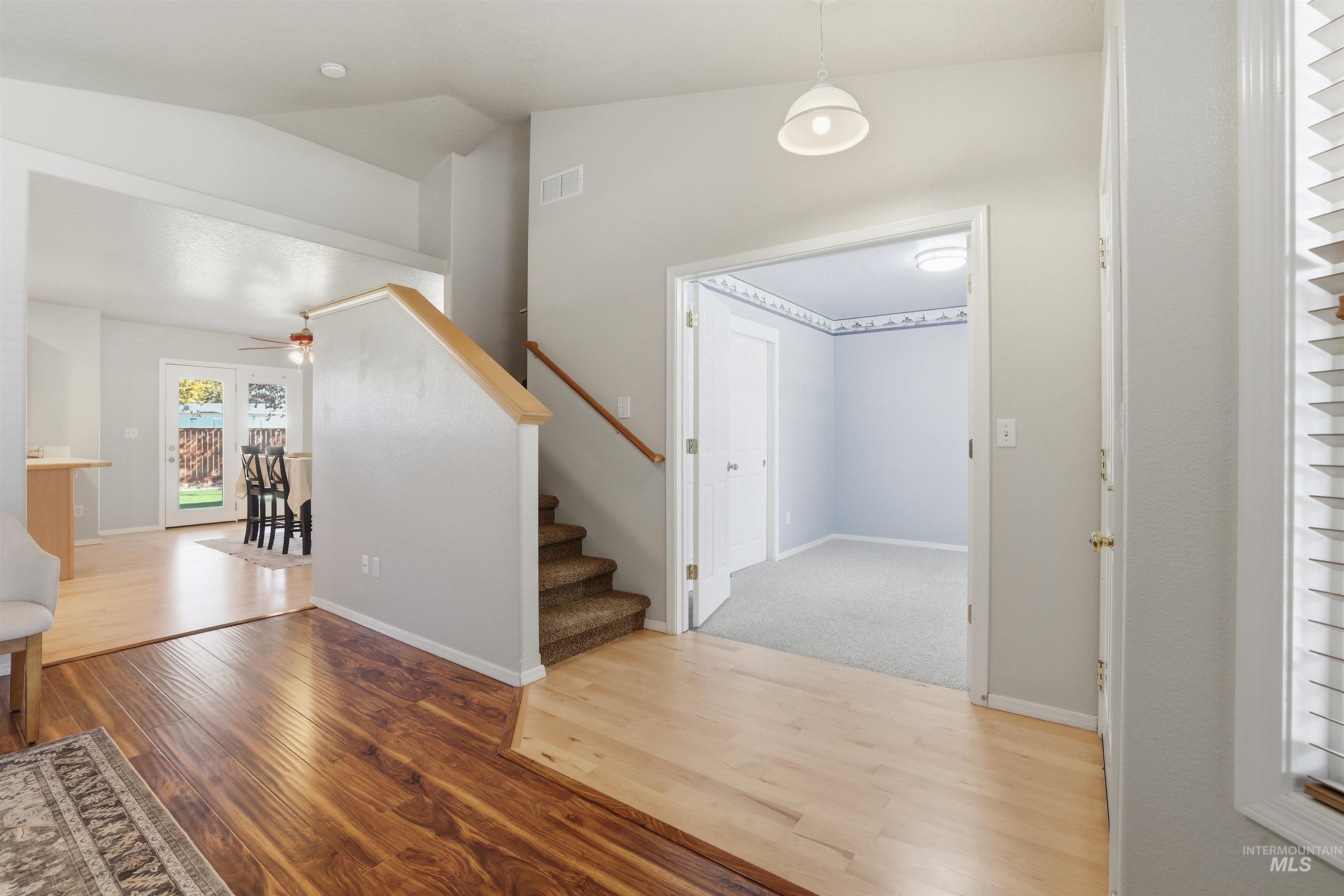 Foyer entrance featuring wood finished floors, lofted ceiling, and stairway