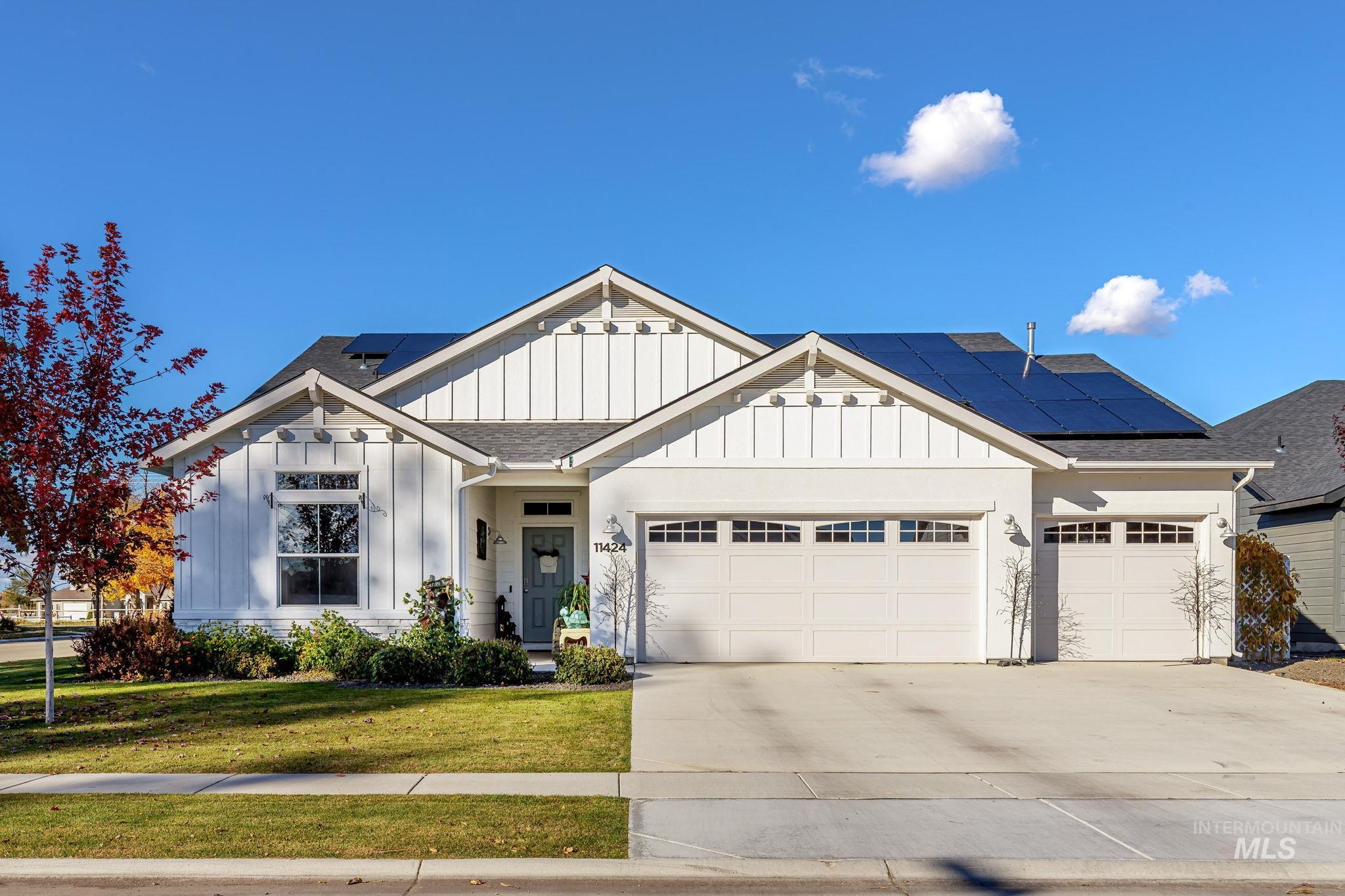 View of front of house featuring board and batten siding, a shingled roof, a front lawn, driveway, and a garage
