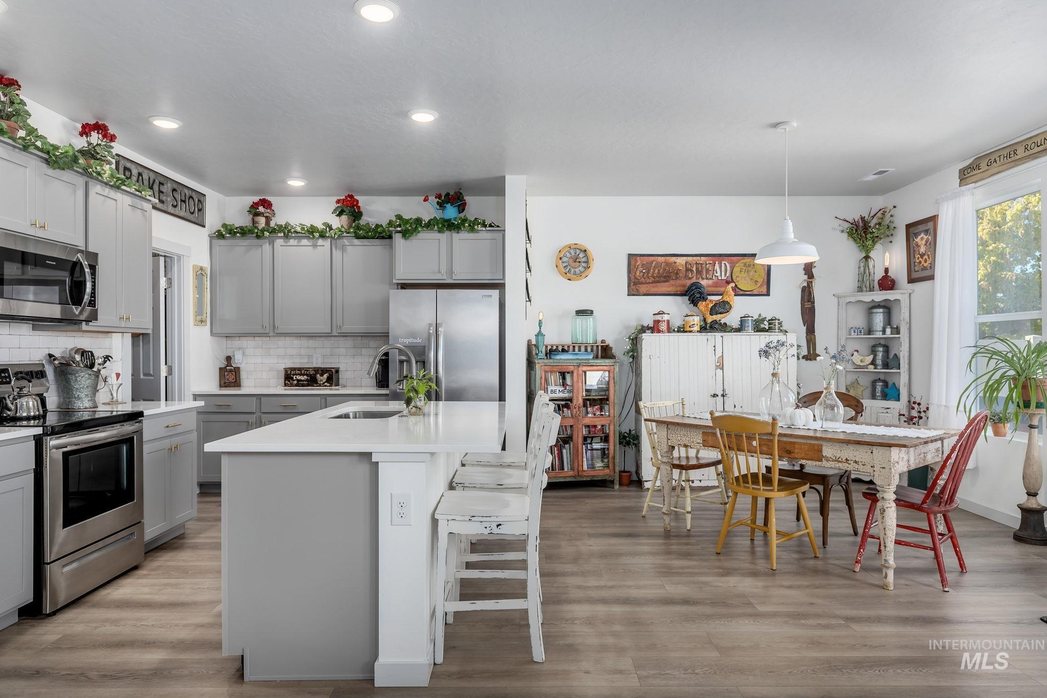 Kitchen featuring stainless steel appliances, tasteful backsplash, a breakfast bar area, light wood-style floors, and recessed lighting