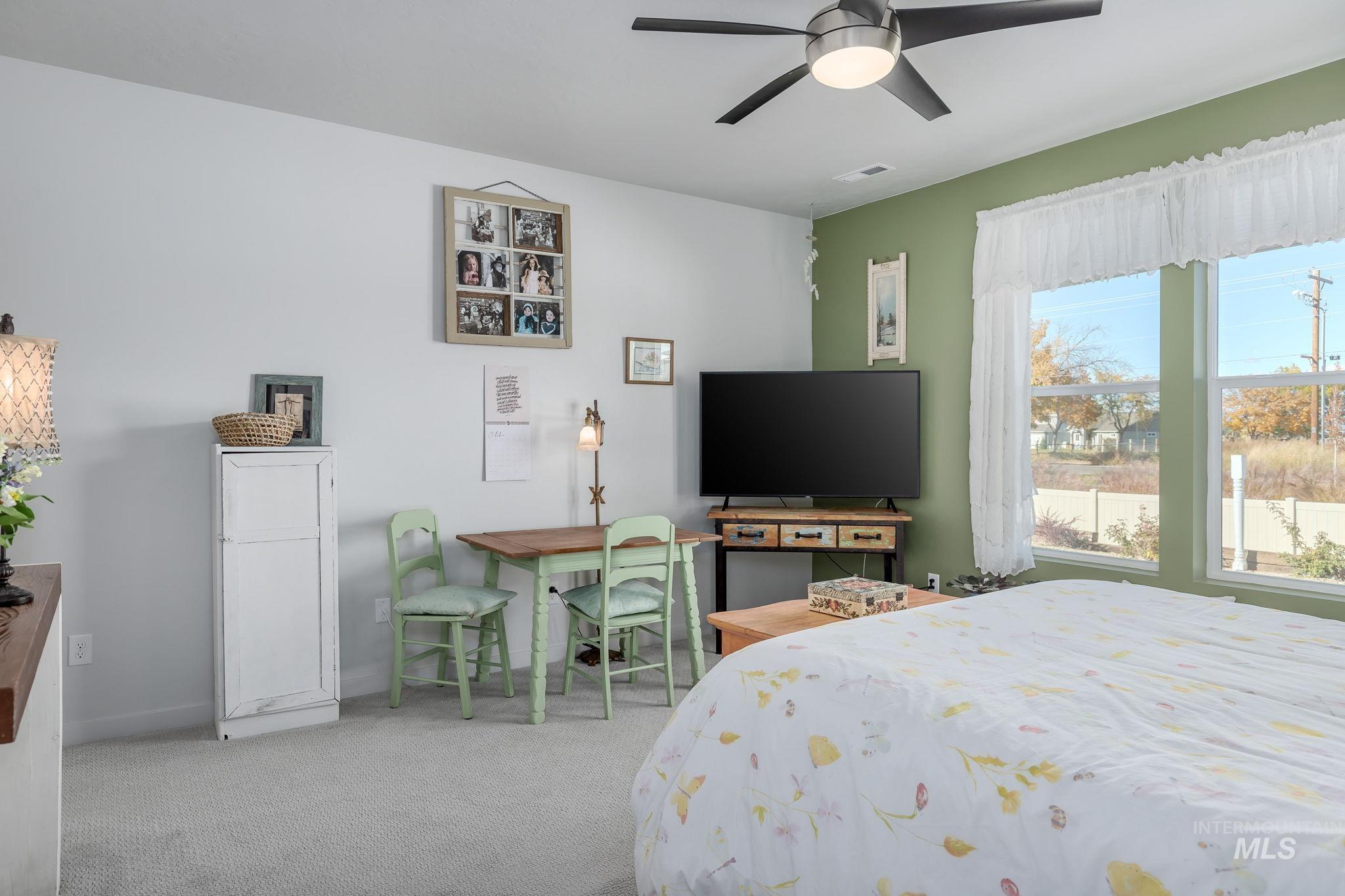 Bedroom with light colored carpet and a ceiling fan
