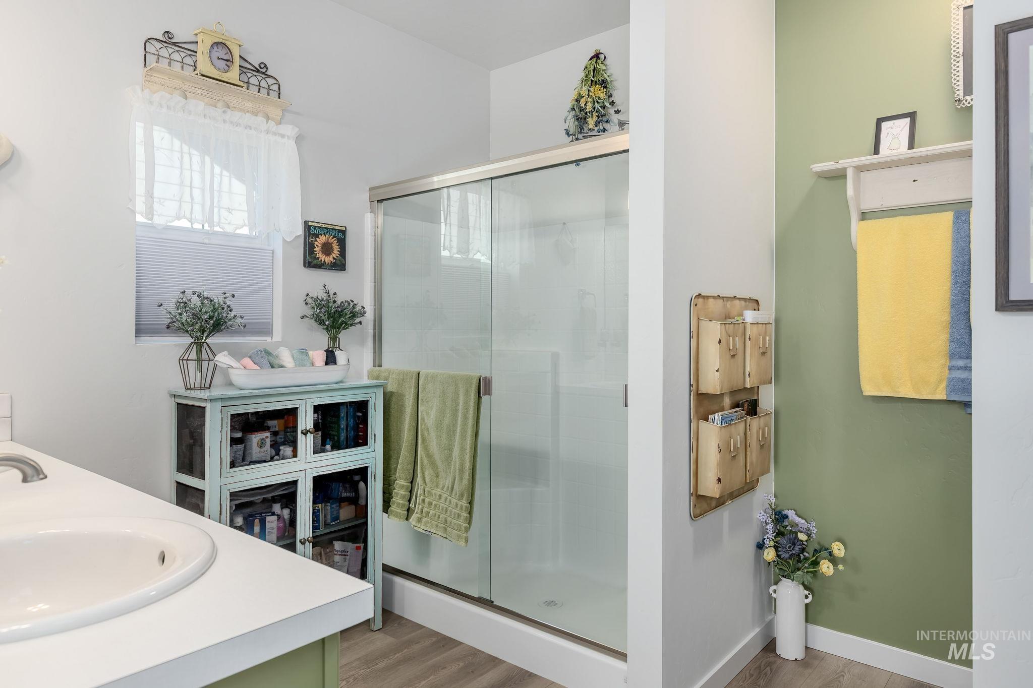 Bathroom with double vanity, a stall shower, and light wood finished floors