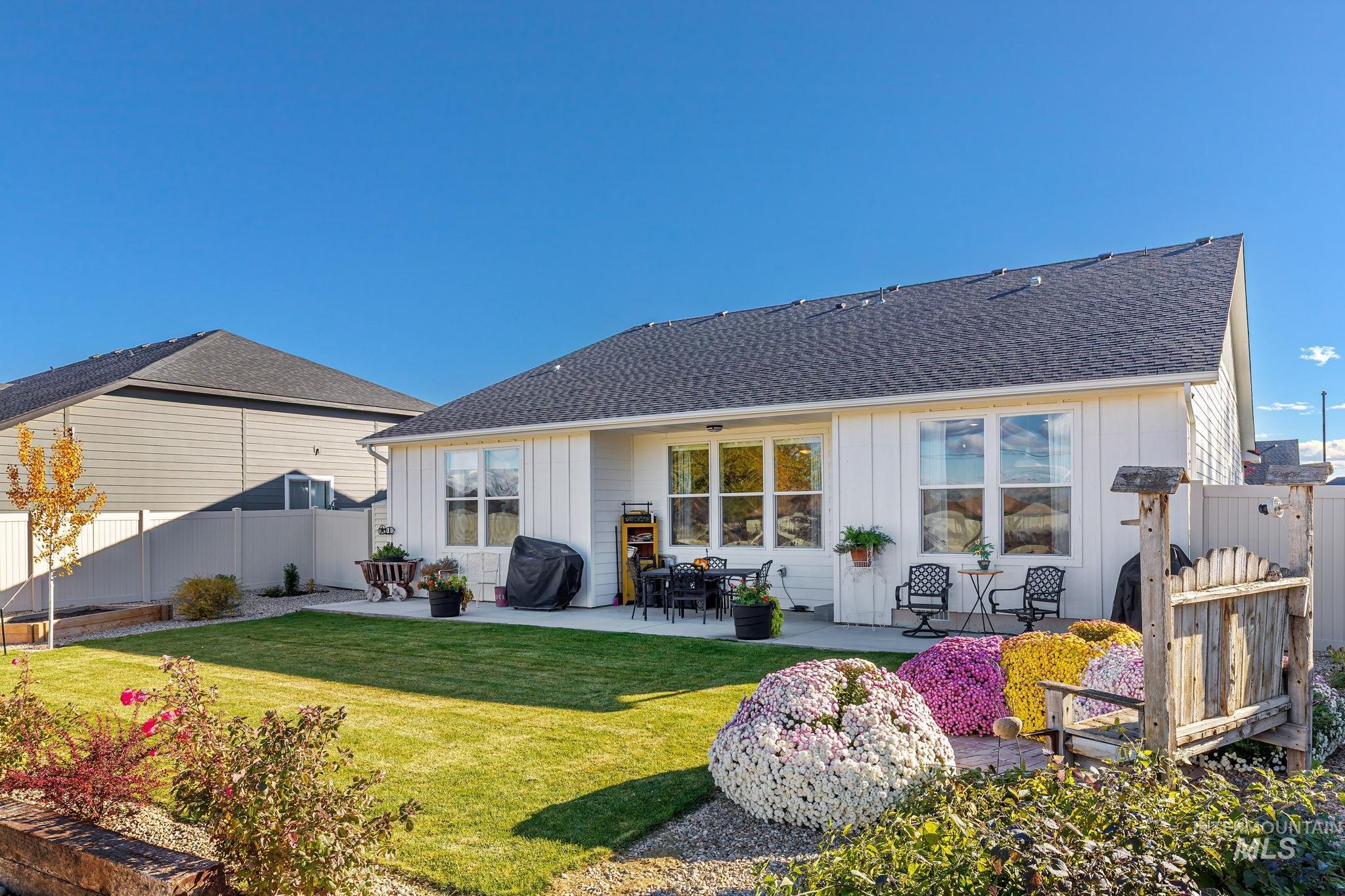 Back of property featuring board and batten siding, a patio, and roof with shingles
