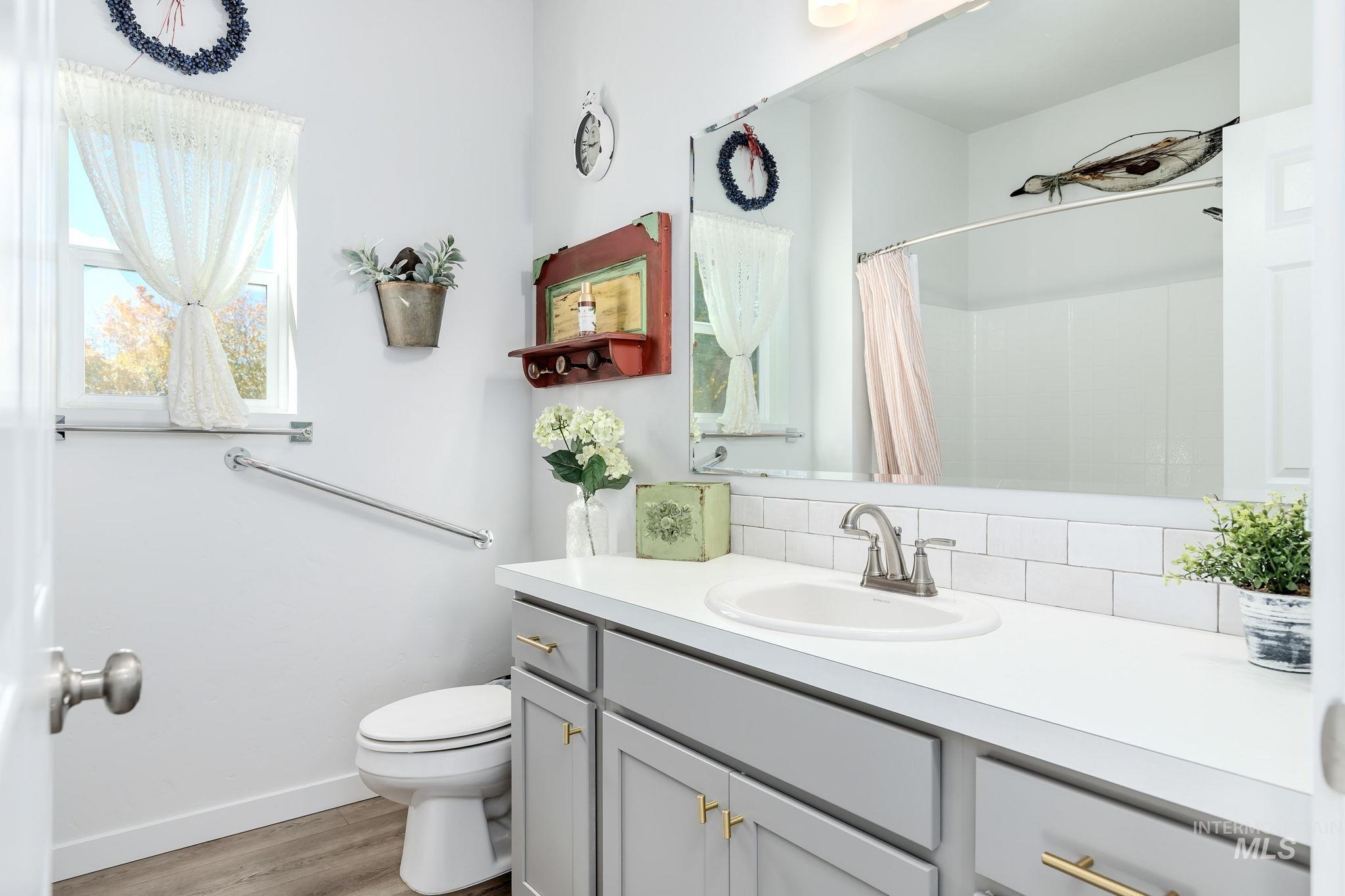 Bathroom featuring vanity, light wood-type flooring, a shower with curtain, and decorative backsplash