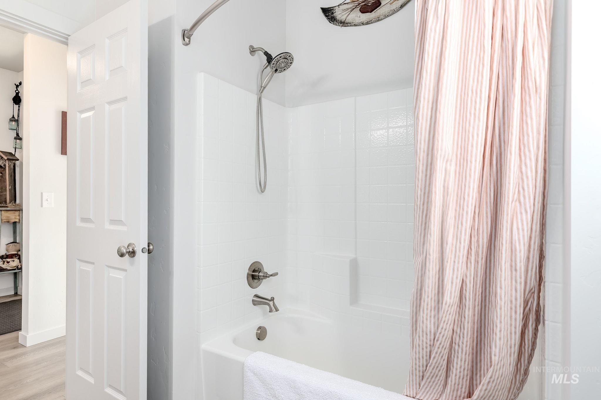Full bath with shower / tub combo and wood finished floors