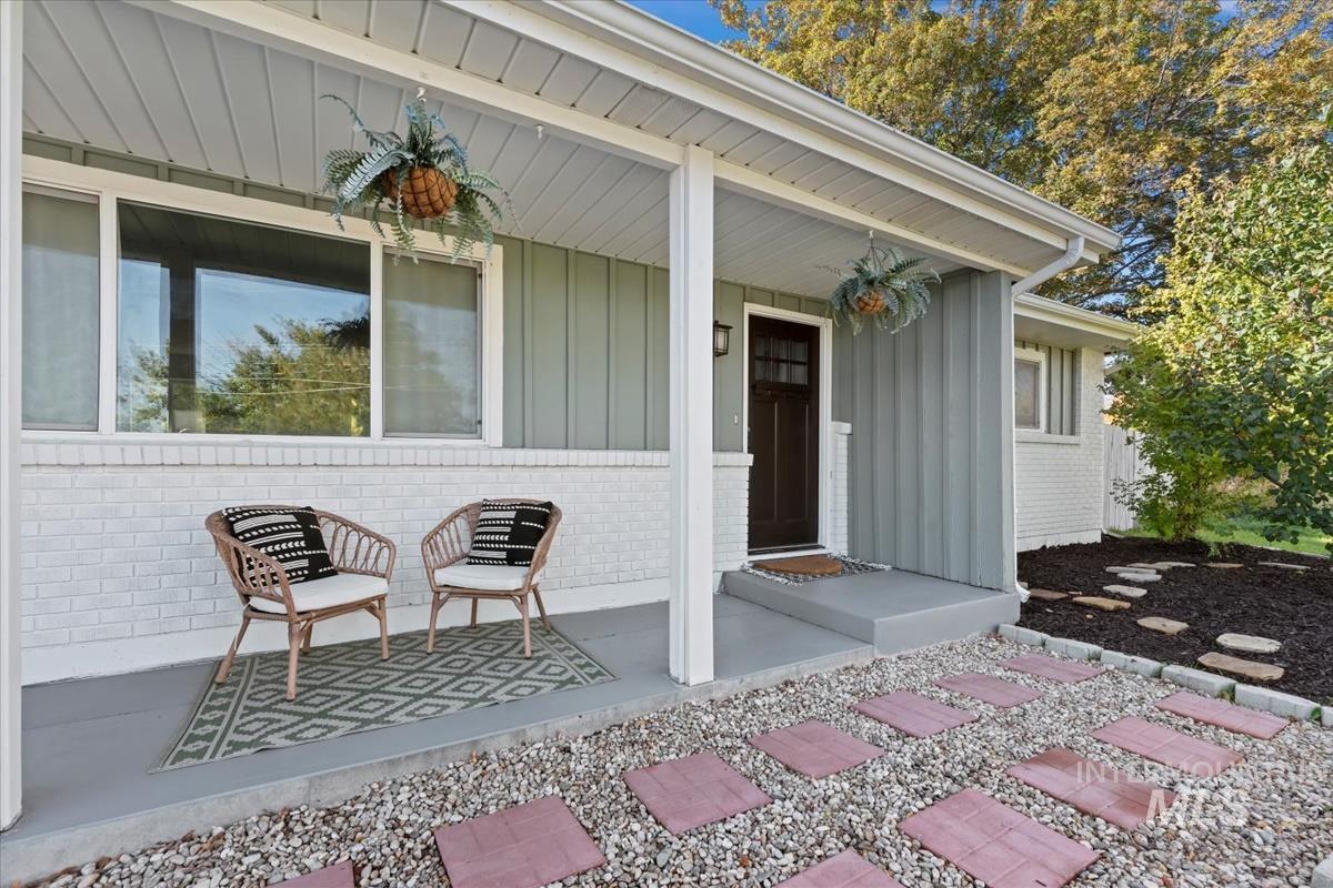 Property entrance with a porch, board and batten siding, and brick siding