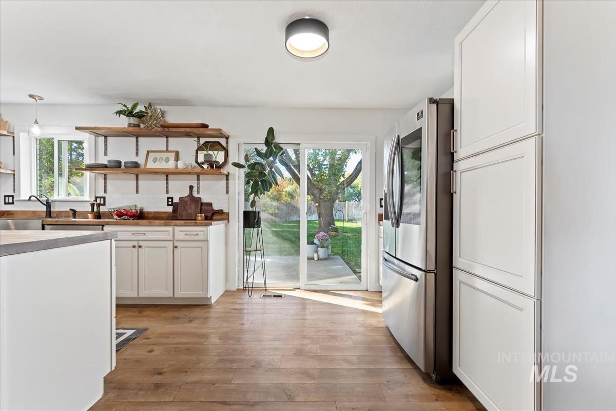 Kitchen featuring white cabinets, stainless steel fridge with ice dispenser, healthy amount of natural light, and light wood finished floors