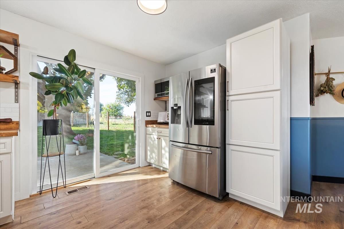 Kitchen featuring appliances with stainless steel finishes, white cabinets, and light wood-style flooring