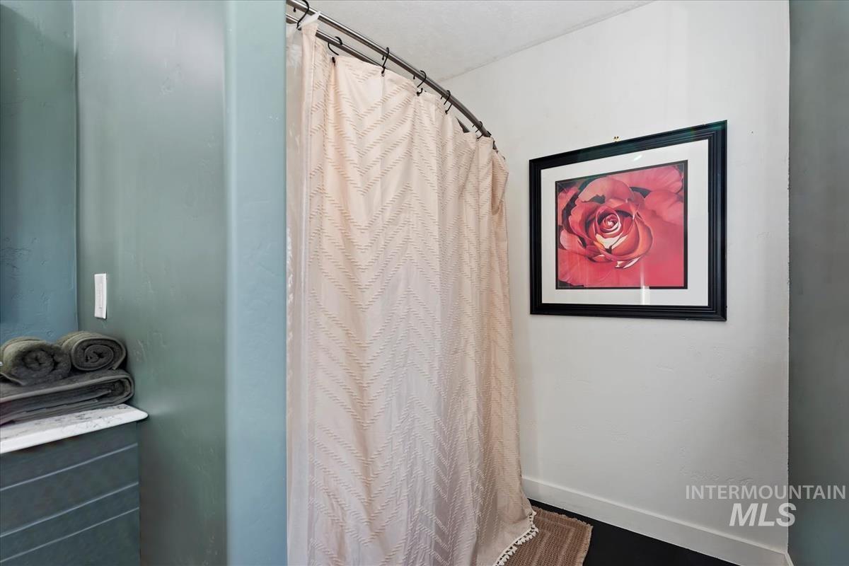 Full bath featuring a shower with curtain and baseboards