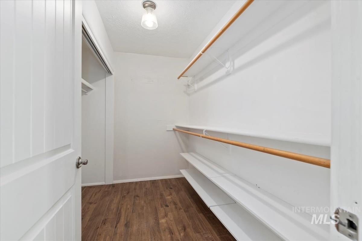 Spacious closet with dark wood-type flooring