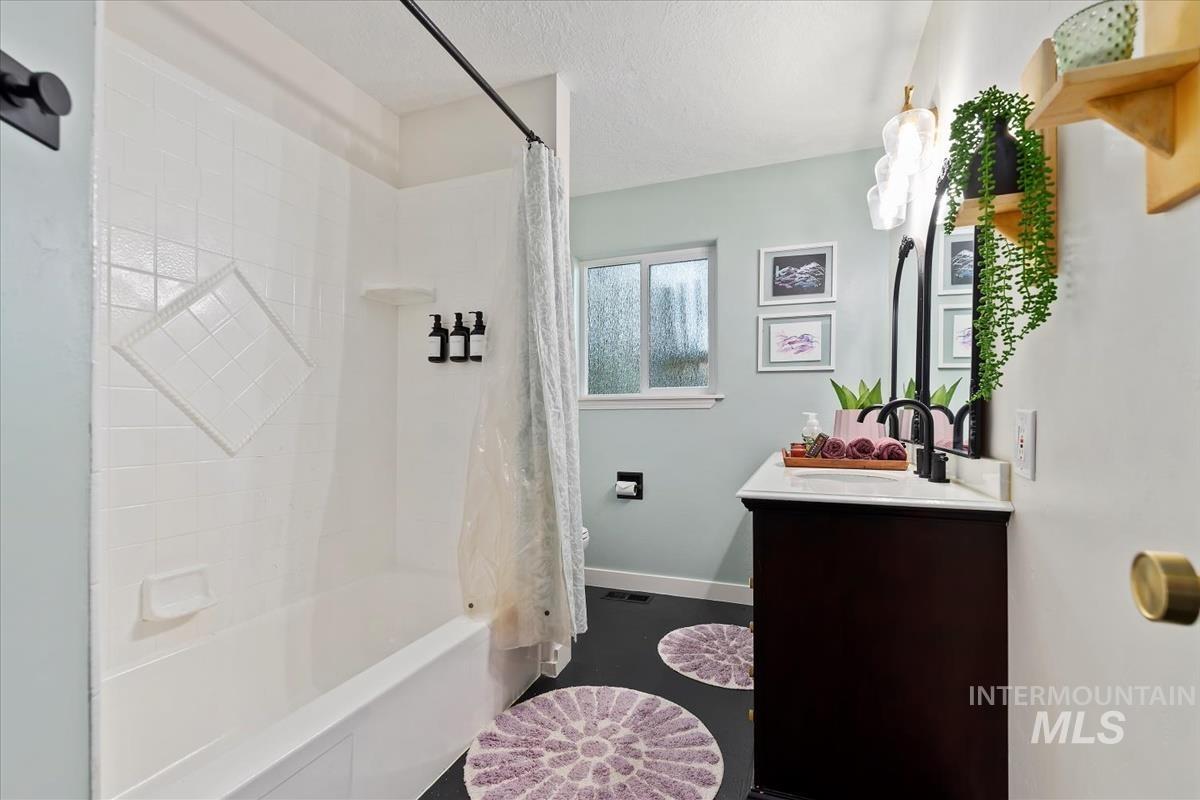 Full bathroom featuring vanity, shower / bath combo with shower curtain, and a textured ceiling