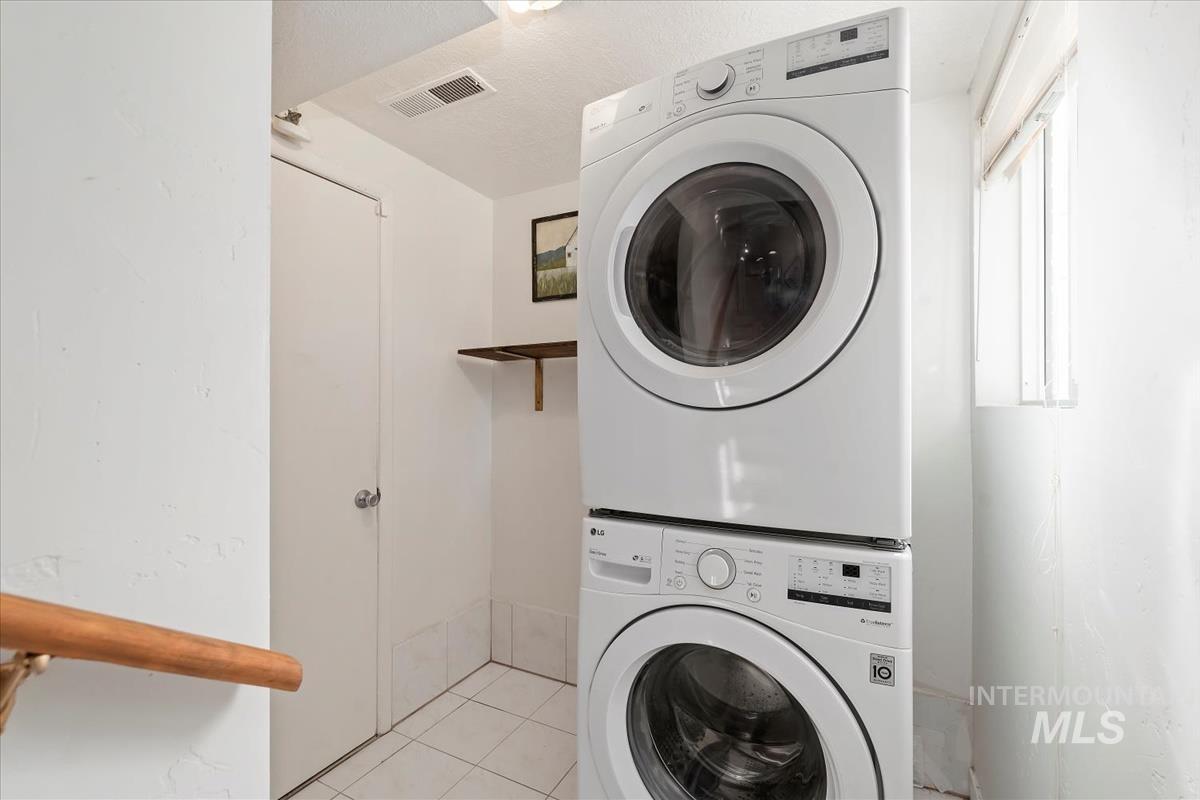 Laundry room featuring light tile patterned flooring and estacked washer and dryer
