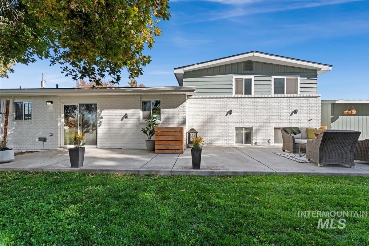 Back of property featuring a patio, a lawn, brick siding, and outdoor lounge area