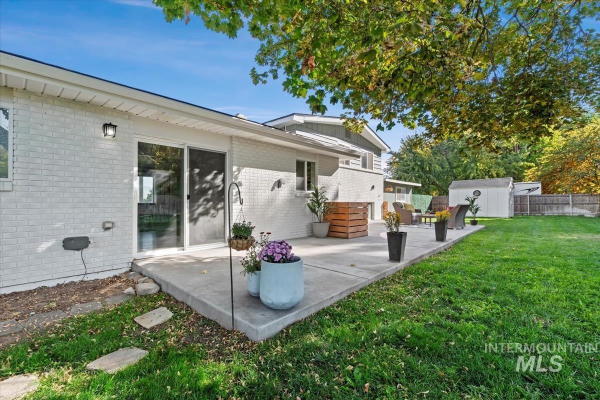 Back of property with a shed, brick siding, and a patio