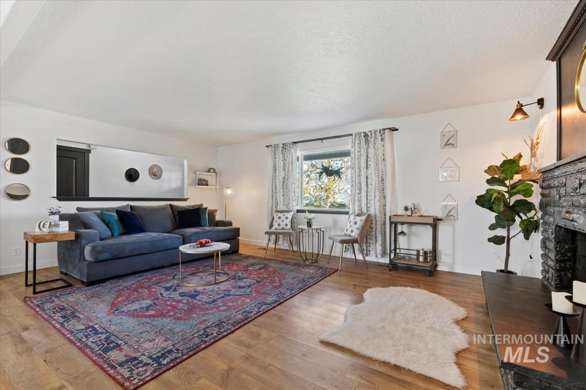 Living room with a stone fireplace, a textured ceiling, and light wood-type flooring