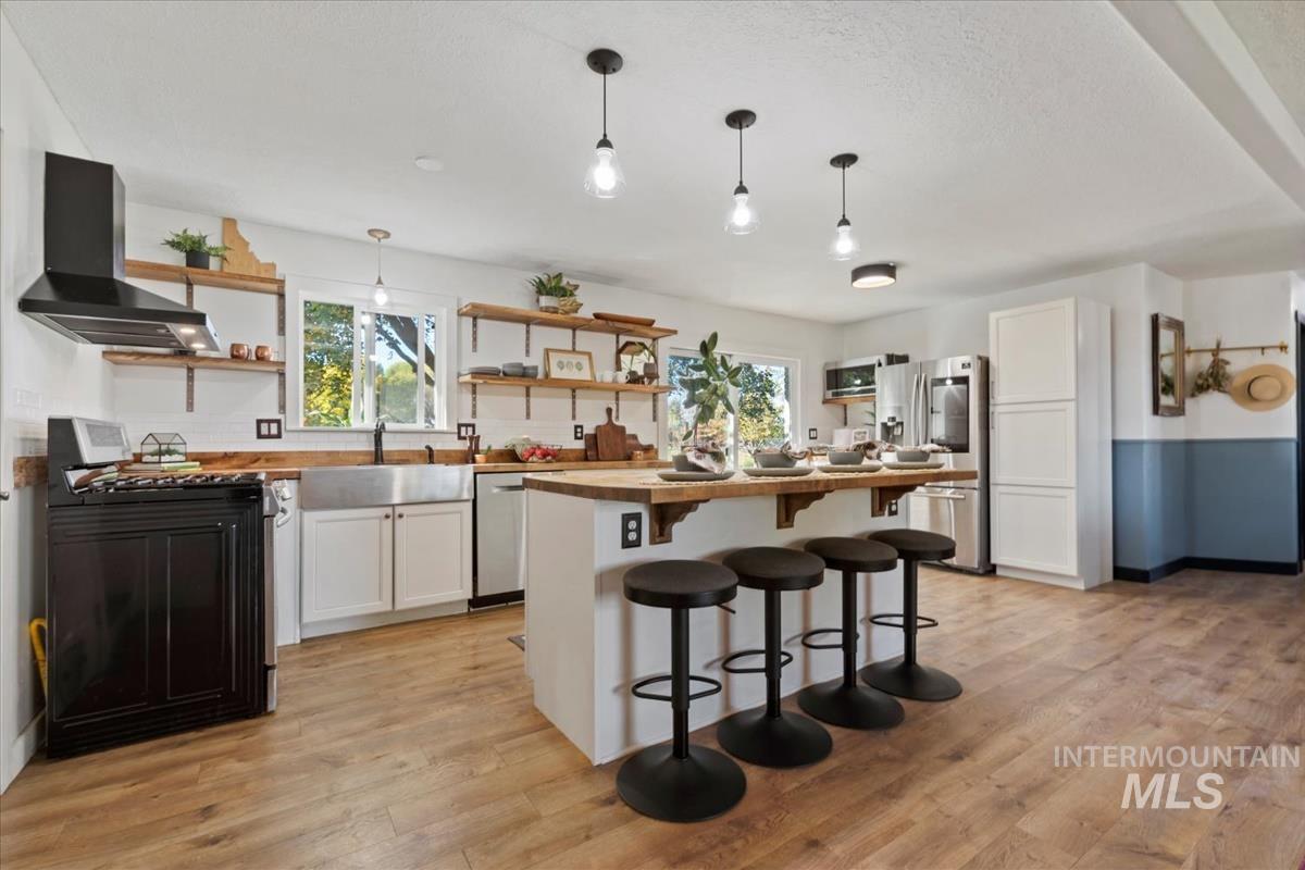 Kitchen featuring a breakfast bar, white cabinets, pendant lighting, and appliances with stainless steel finishes