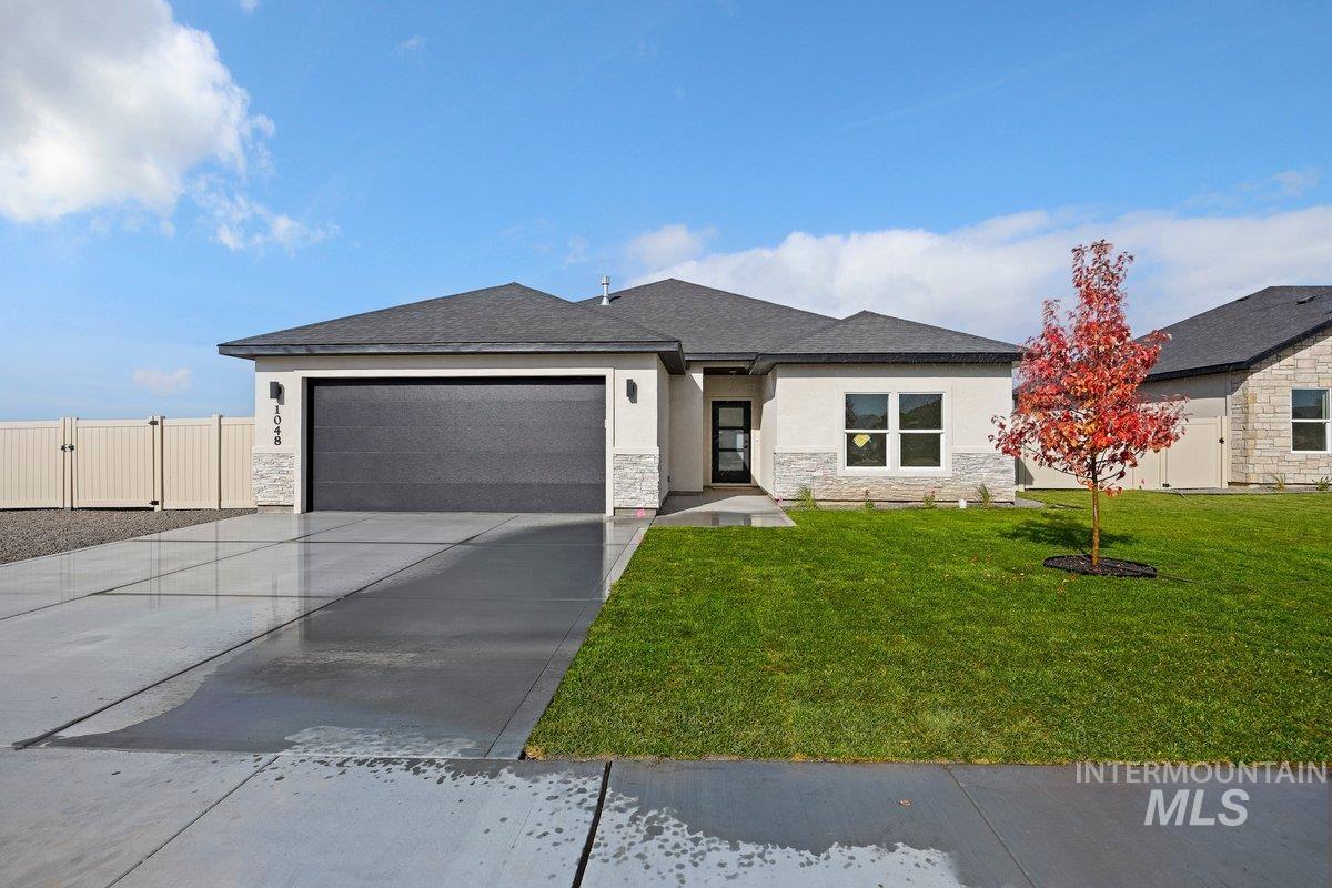 View of front of house featuring stone siding, driveway, an attached garage, and stucco siding