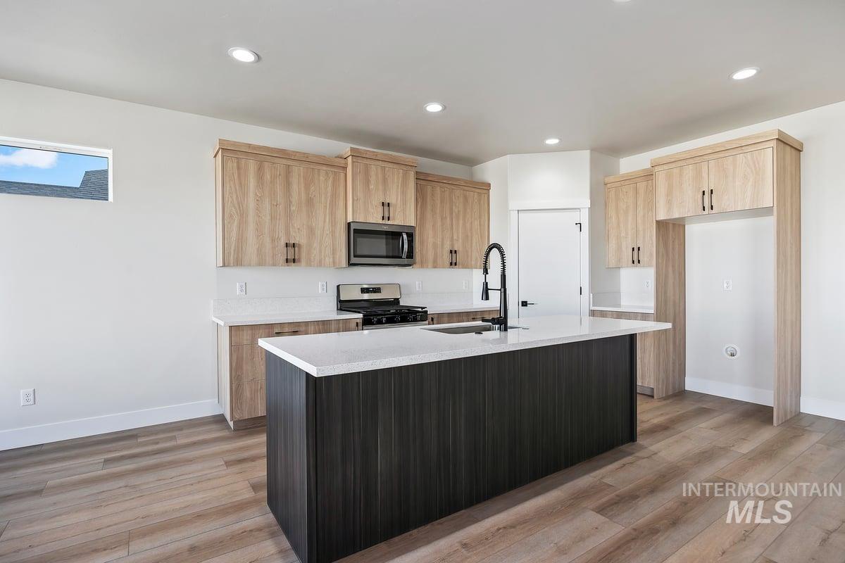 Kitchen with light brown cabinetry, a kitchen island with sink, appliances with stainless steel finishes, light wood-style flooring, and recessed lighting