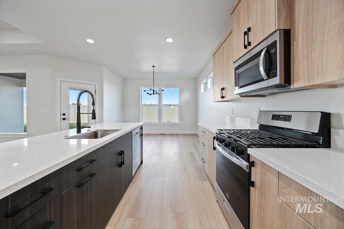 Kitchen featuring appliances with stainless steel finishes, light stone counters, recessed lighting, modern cabinets, and light brown cabinetry