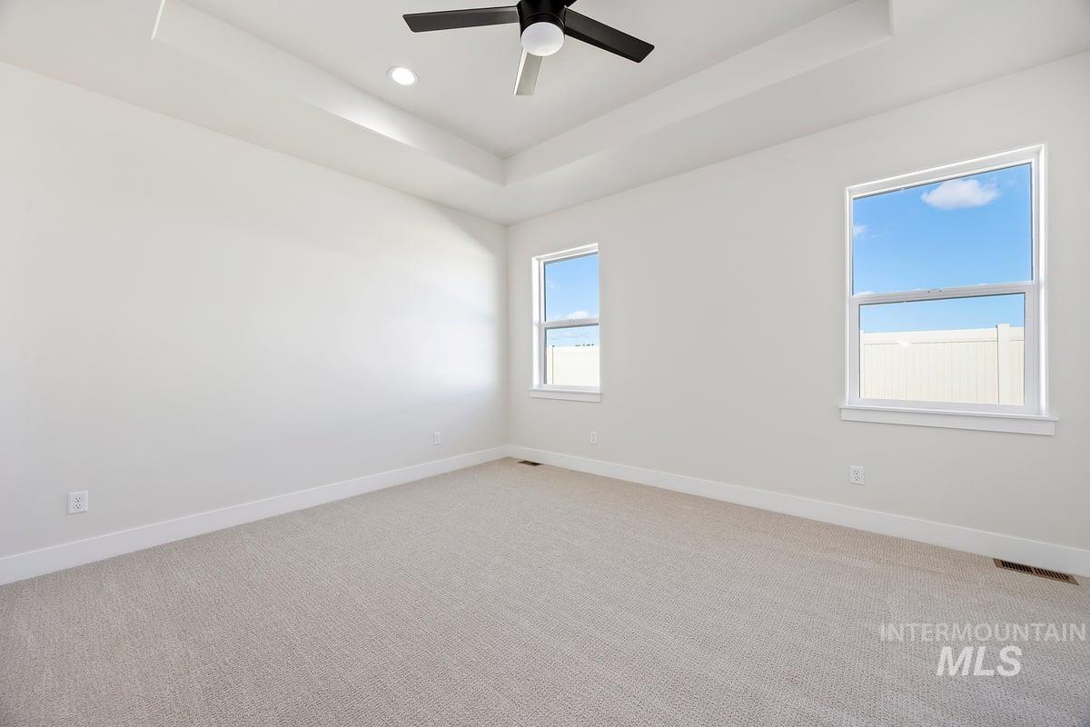 Unfurnished room featuring a tray ceiling, light colored carpet, ceiling fan, and recessed lighting