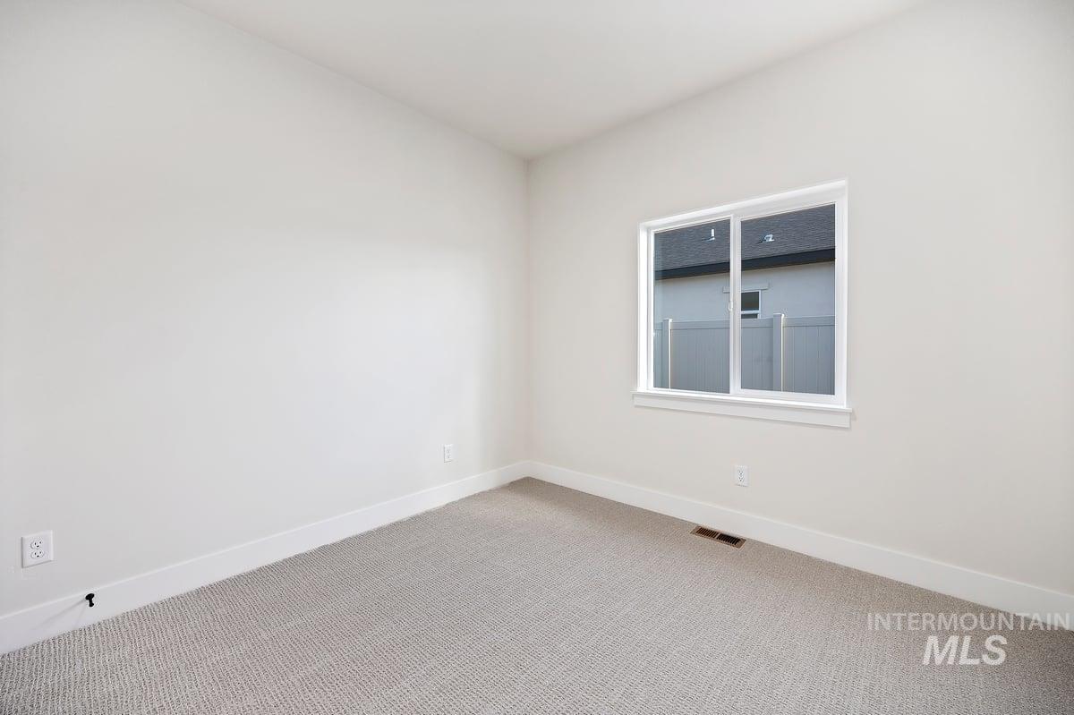 Carpeted spare room featuring baseboards
