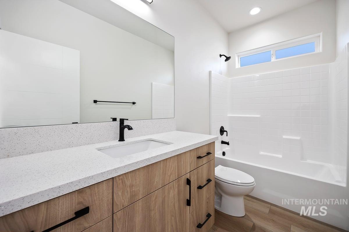 Bathroom with vanity, dark wood finished floors, and shower / washtub combination