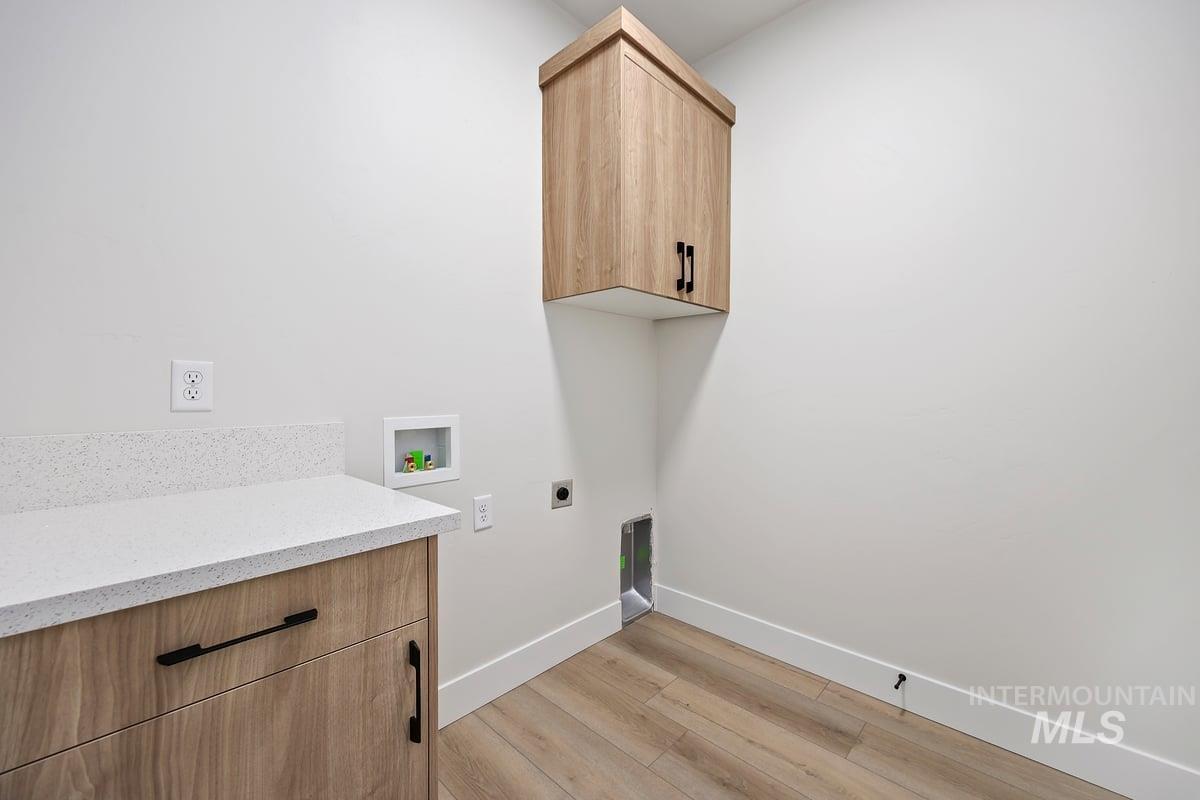Laundry room with light wood-style flooring, electric dryer hookup, cabinet space, and washer hookup