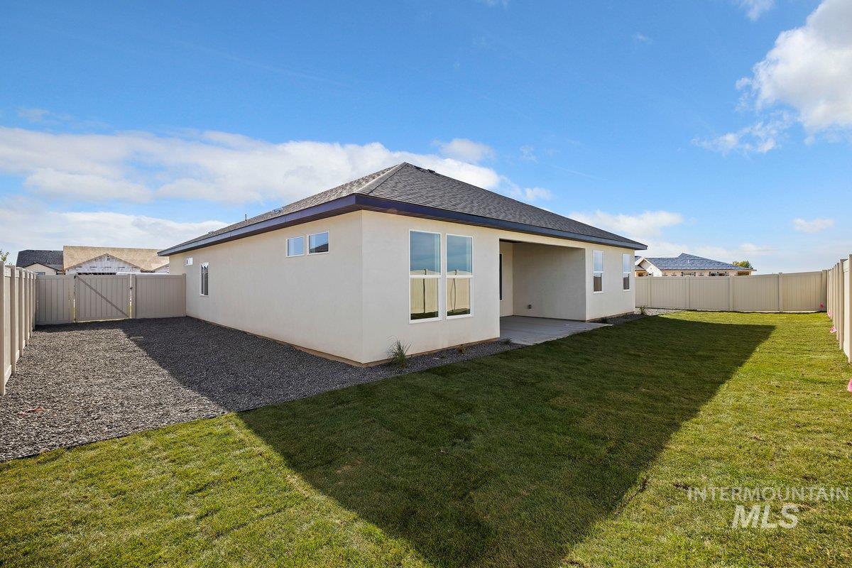 Back of house with a fenced backyard, stucco siding, a patio, roof with shingles, and a gate