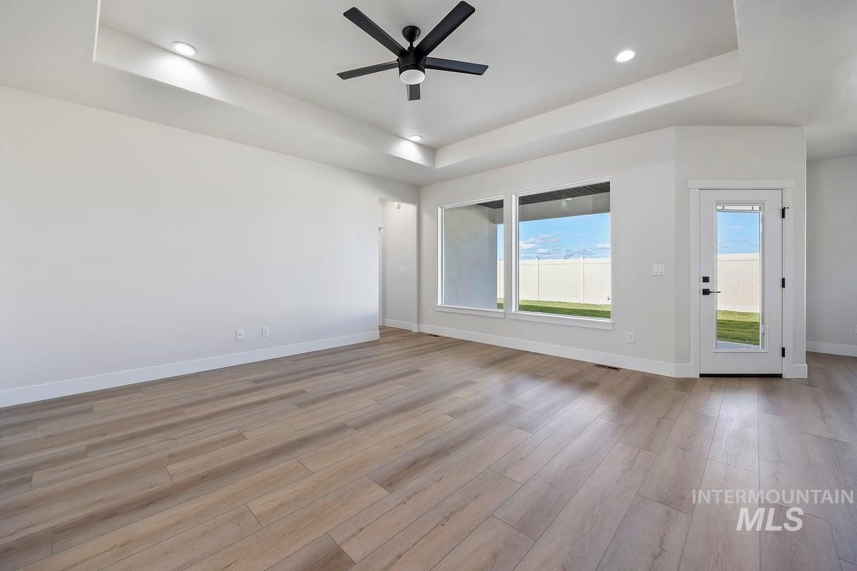 Unfurnished room featuring a tray ceiling, light wood-style floors, ceiling fan, and recessed lighting