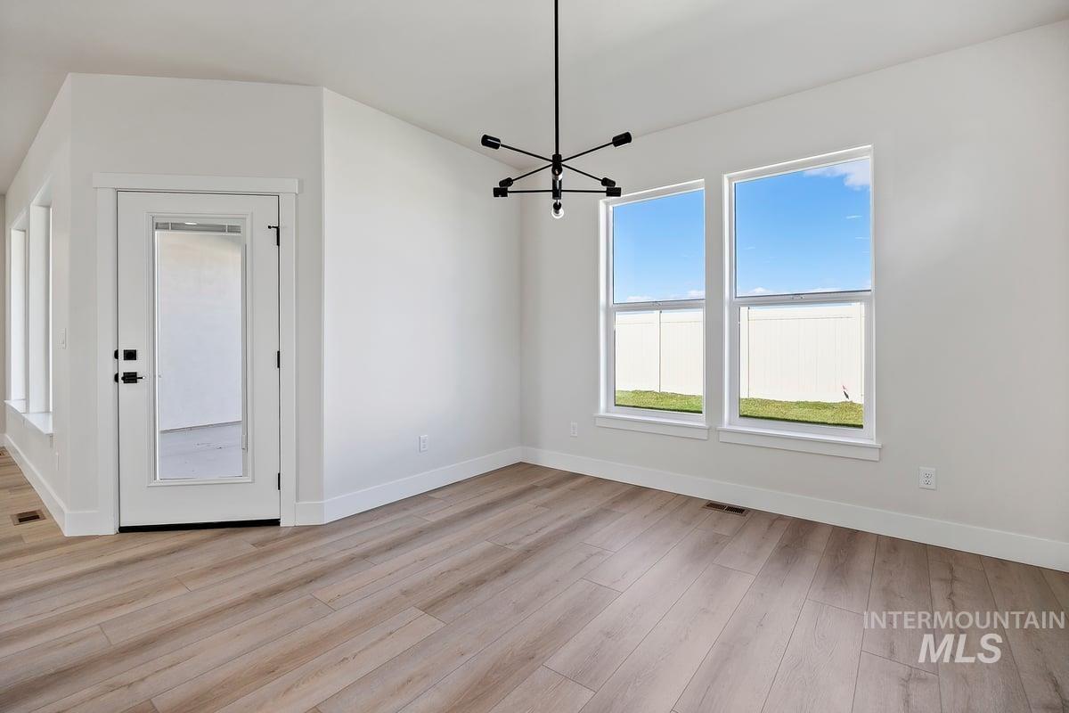 Unfurnished dining area with a chandelier and light wood-style flooring