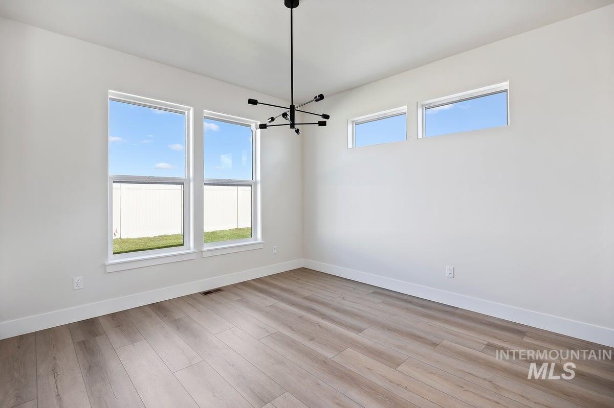 Unfurnished dining area with light wood-type flooring and a chandelier