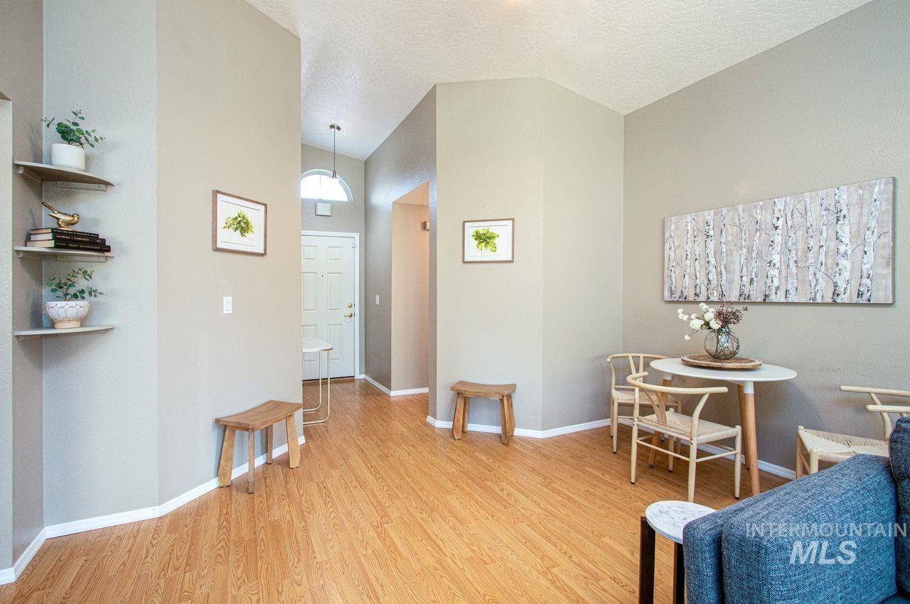 Sitting room featuring light wood-type flooring, a textured ceiling, and vaulted ceiling
