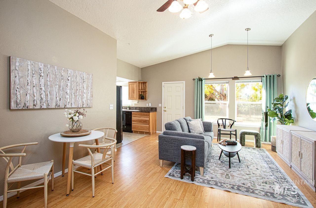 Living area with lofted ceiling, light wood-type flooring, a textured ceiling, and ceiling fan