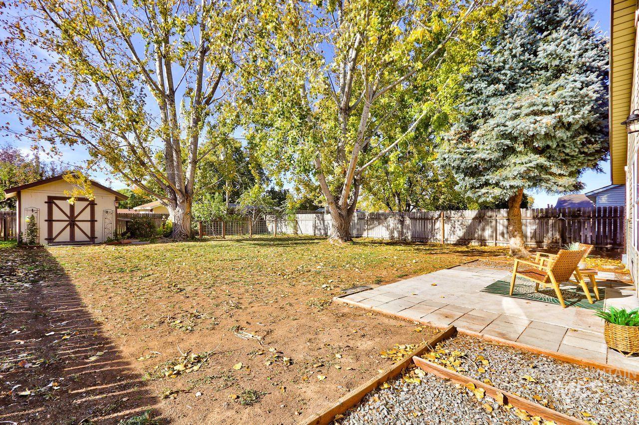 Fenced backyard with a storage unit and a patio