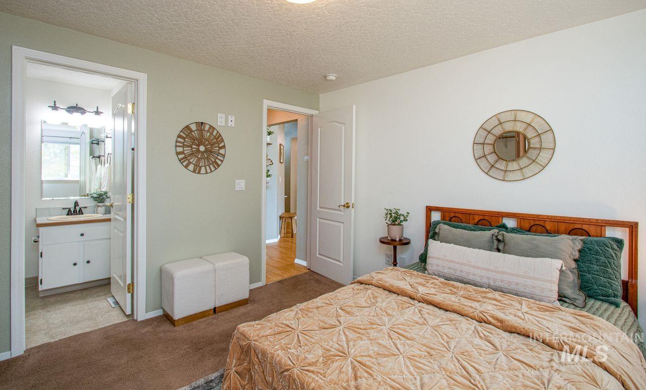 Carpeted bedroom with a textured ceiling and ensuite bath