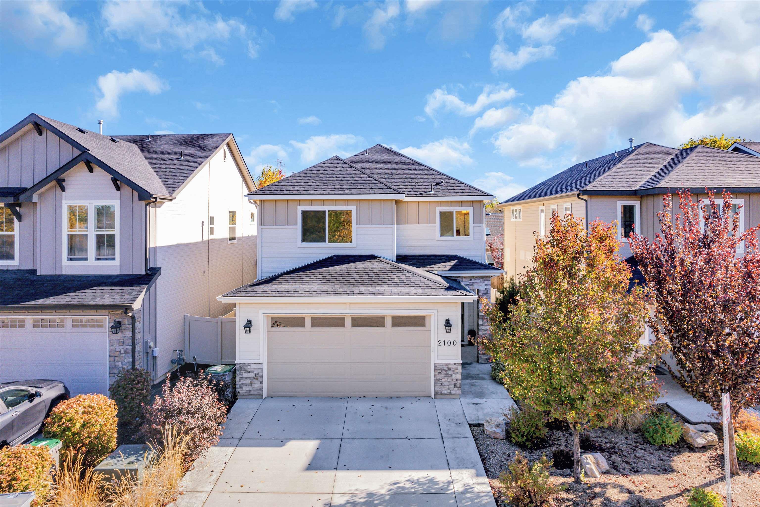 View of front facade featuring roof with shingles, stone siding, board and batten siding, driveway, and a garage